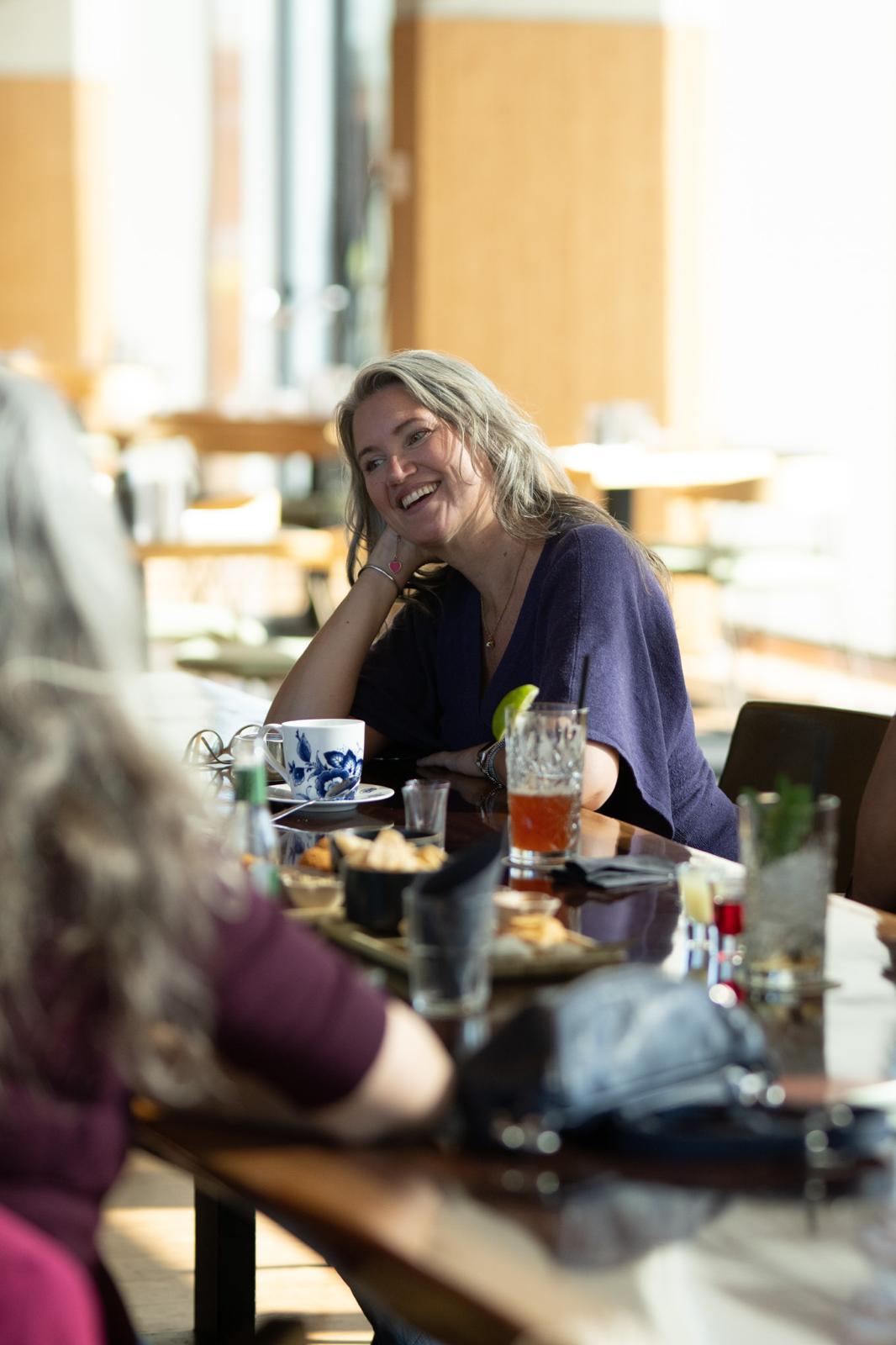 Gwen aan tafel, lachend in gesprek met een andere ondernemer